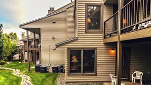 A two-story house with a covered patio, outdoor seating, and a landscaped garden. - Sunburst Condominiums (Steamboat Springs)