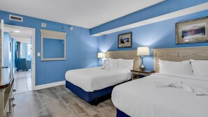 Een hotelkamer met twee bedden, een grote spiegel en een ingelijste foto aan de muur.
