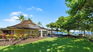 A house with a sloped roof, a covered patio with outdoor furniture, and a view of the ocean.