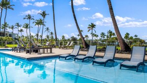 A pool area with lounge chairs and palm trees.