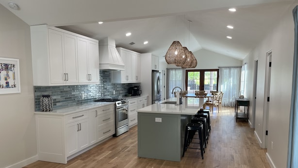 A modern kitchen with white cabinets, a large island, and a dining area with a table and chairs. - Close to Village & Pier, quiet retreat, bunk room  with toys, games, books & TV (St. Simons Island)