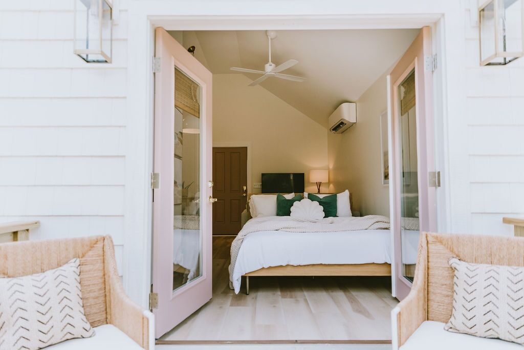Ein Schlafzimmer mit einem Bett, zwei Stühlen, einem Deckenventilator und einer Klimaanlage.