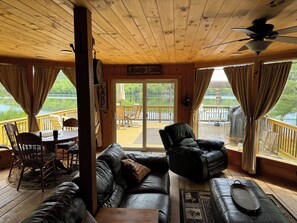 Ein gemütliches Blockhaus-Interieur mit Ledersofa, Esstisch und Seeblick.