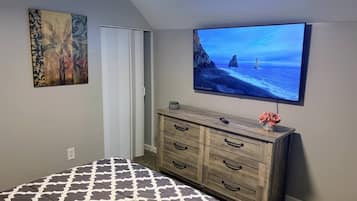 A bedroom with a bed, a dresser, a television, and a painting on the wall.