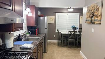 A compact kitchen with a gas stove, stainless steel appliances, and a dining area with a table and chairs.