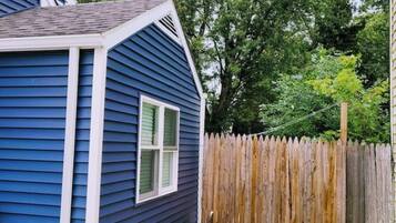 A blue house with a wooden fence and a concrete pathway.