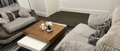 A living room with a sofa, a coffee table with decorative items, and a rug.