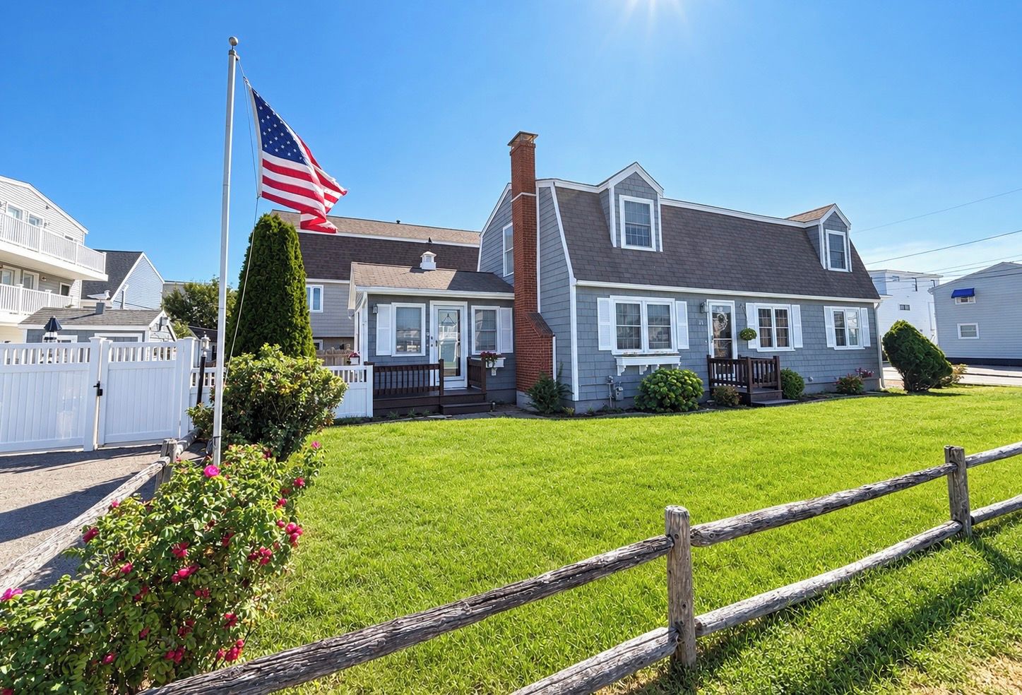 A residential house with a well-maintained lawn, a wooden fence, and an American flag.