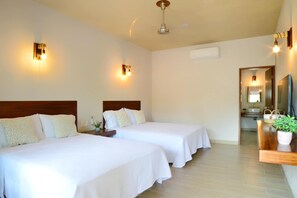 A hotel room with two beds, a wooden headboard, a nightstand, a potted plant, and a bathroom visible through an open door. - Natura Hotel y Villas (Zihuatanejo)