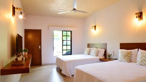 A hotel room with two beds, a ceiling fan, a window, and a wooden bench with a basket and plants. - Natura Hotel y Villas  (Zihuatanejo)