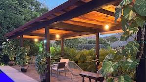 An outdoor patio with a pool, wooden pergola, seating, and lush greenery. - Natura Hotel y Villas  (Zihuatanejo)