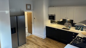 Eine moderne Küche mit Edelstahlgeräten, schwarzen Schränken und einer Holztür.