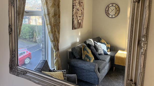 Ein Wohnzimmer mit einer Couch, Zierkissen, einer Uhr und einem Gemälde an der Wand.