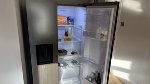 Ein moderner Kühlschrank mit mehreren Ablagen und Fächern, darunter eine Gefrierablage, eine Milchkarton und eine Weinflasche.