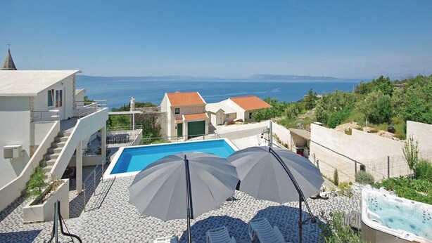 Un área de piscina en la azotea con vistas despejadas al mar, una piscina y un jacuzzi.