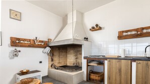 Una cocina con estufa integrada, taburetes de madera, un farol colgante y una chimenea de ladrillo.