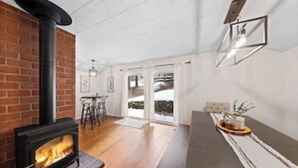 Een moderne woonkamer met een haard van baksteen, houten vloeren en een eethoek met een bar.