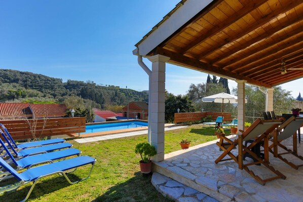 Un espacio al aire libre cubierto con piscina, sillones de descanso y un patio de piedra.
