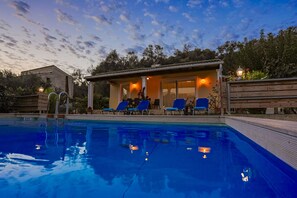 Una piscina con sillas de descanso y una zona de estar techada.