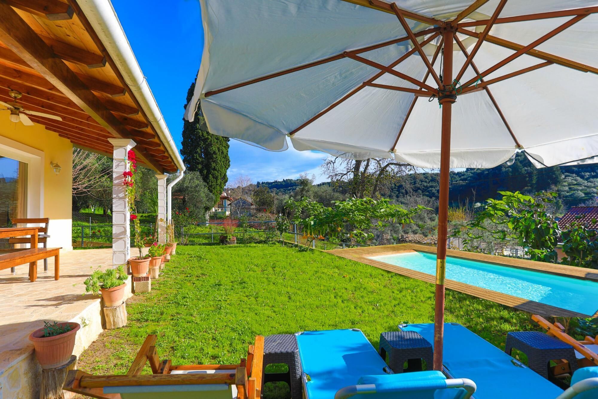 Un área junto a la piscina con terraza de madera, sillas de descanso y una sombrilla.