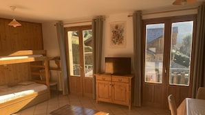 A cozy room with a bunk bed, a wooden cabinet, a television, and a table. - 42 m2 apartment, ideal for a spa treatment in Brides or skiing in the 3 valleys. (salins fontaine)