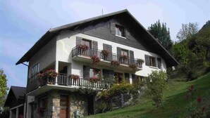 A two-story chalet with a stone facade, balconies with flower boxes, and a stone retaining wall. - 42 m2 apartment, ideal for a spa treatment in Brides or skiing in the 3 valleys. (salins fontaine)