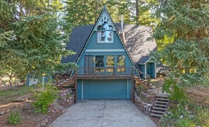Une maison avec un toit à forte pente, une véranda à l’avant avec une balustrade et une porte de garage.