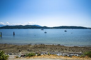 Ein ruhiger See mit mehreren Booten, einer felsigen Uferlinie und einer bewaldeten Insel in der Ferne.