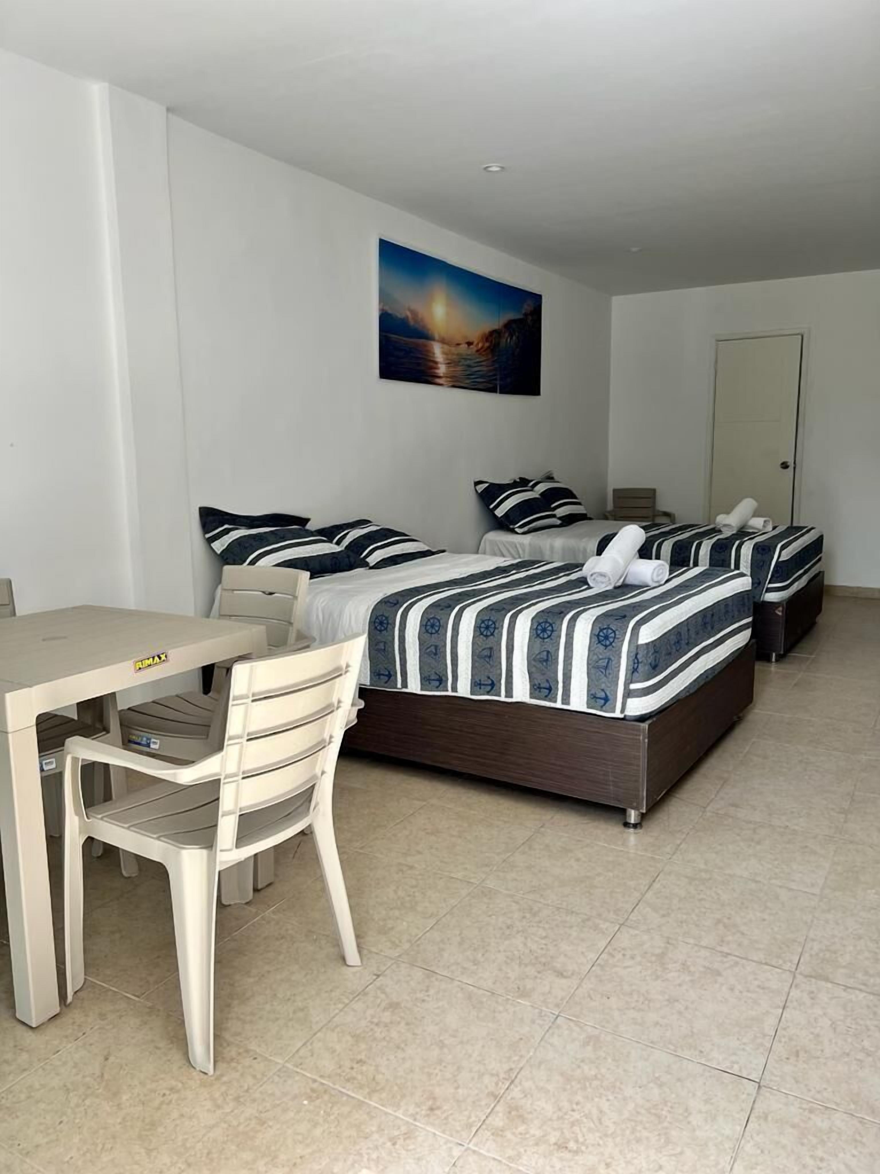 A bedroom with two beds, a desk, and a chair.