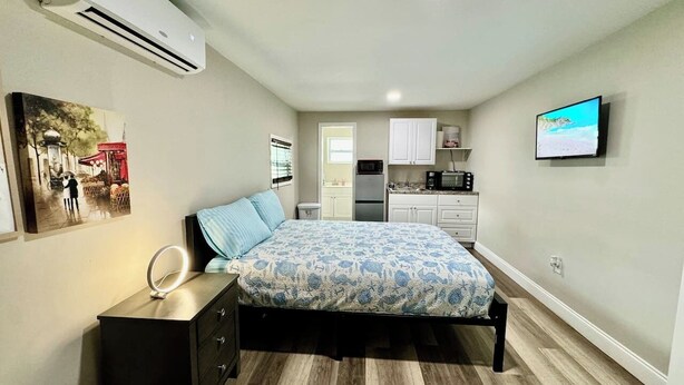 A bedroom with a bed, bedside table, and a TV mounted on the wall.