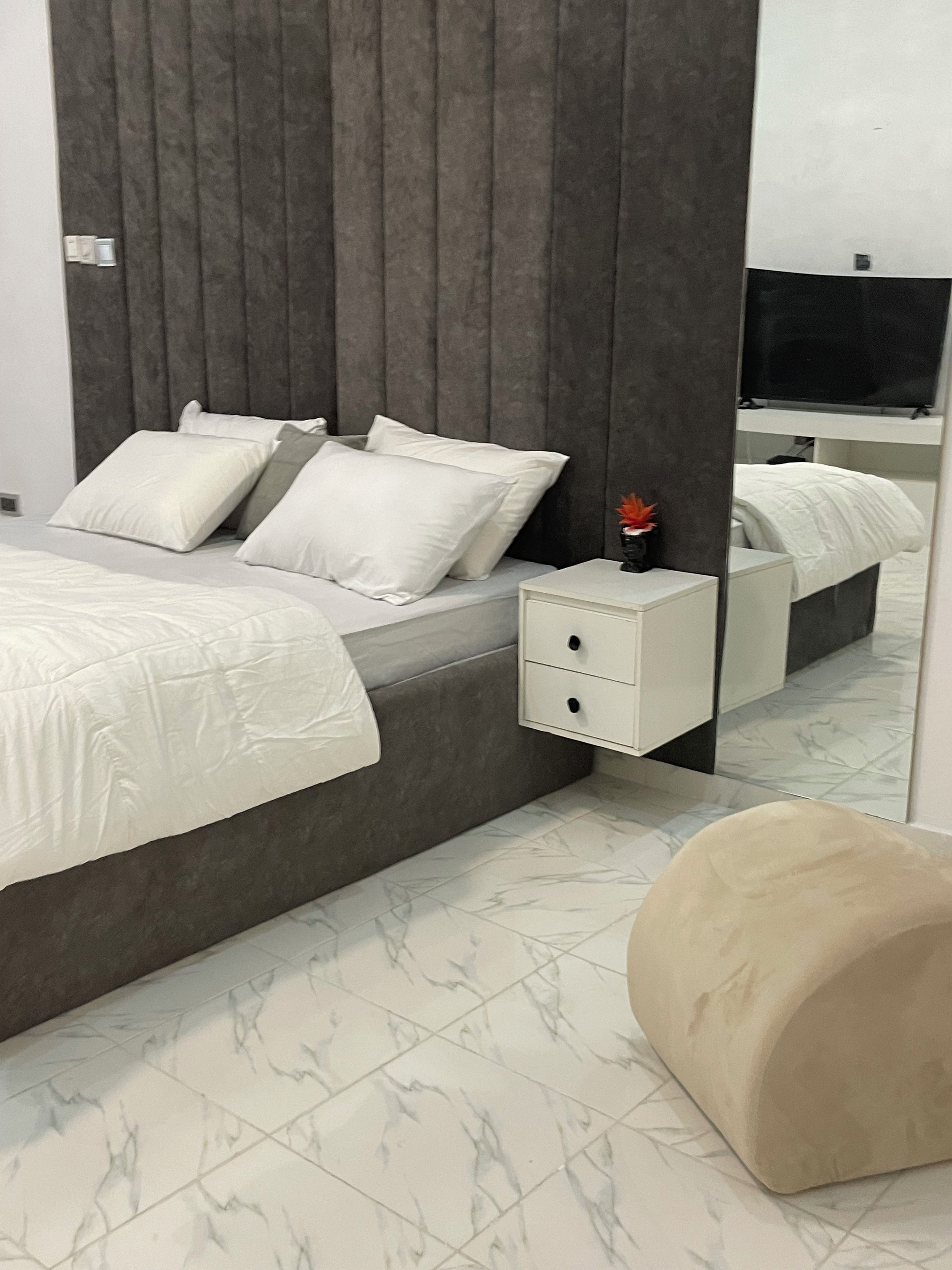 A modern bedroom with a bed, nightstand, and a large mirror.