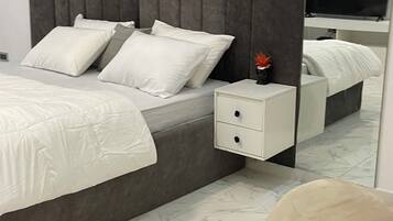 A modern bedroom with a bed, nightstand, and a large mirror.