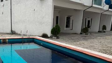 A residential building with a swimming pool, a covered patio, and a satellite dish.