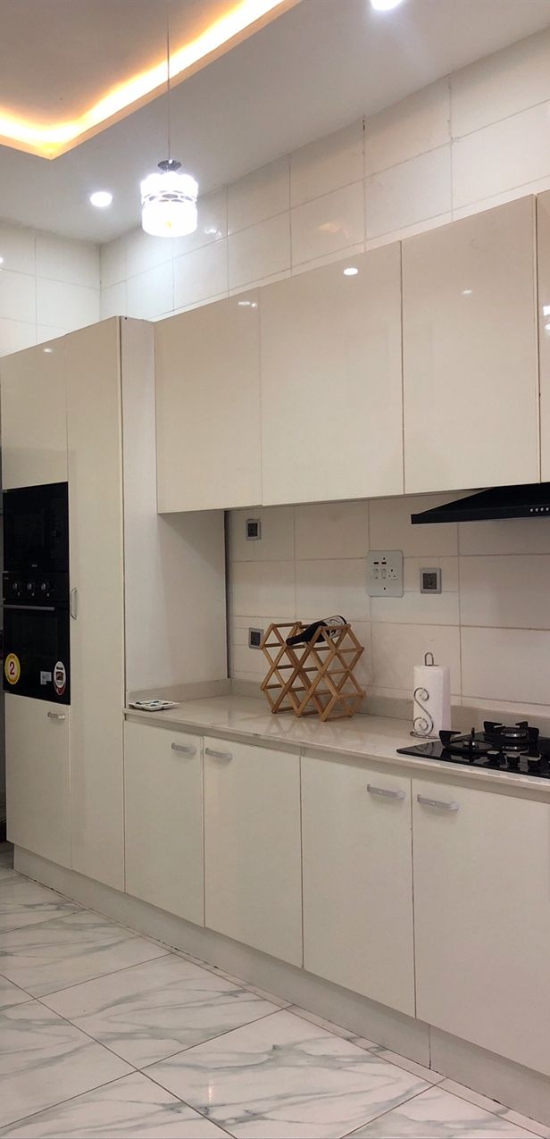 A modern kitchen with white cabinets, a gas stove, and a built-in oven.