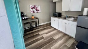 A compact kitchen with a microwave, sink, and white cabinets.