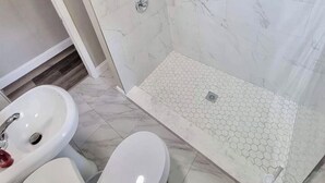 A bathroom with a shower, two sinks, and a toilet.