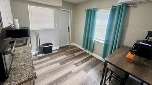 A compact kitchen with a countertop, sink, and a dining area with a table and chairs.