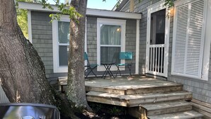 A covered patio with a wooden deck, two chairs, and a grill. - Pet friendly!  Across from the Pools!  Includes a golf cart! (Surfside Beach)