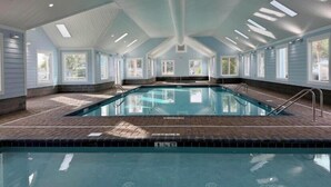 An indoor swimming pool with a tiled floor, surrounded by windows and a high ceiling with skylights. - Pet friendly!  Across from the Pools!  Includes a golf cart! (Surfside Beach)