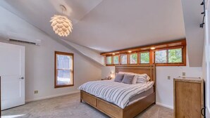 Et soveværelse med en seng, et træsengegærde, en loftlampe, et vindue og en dør.