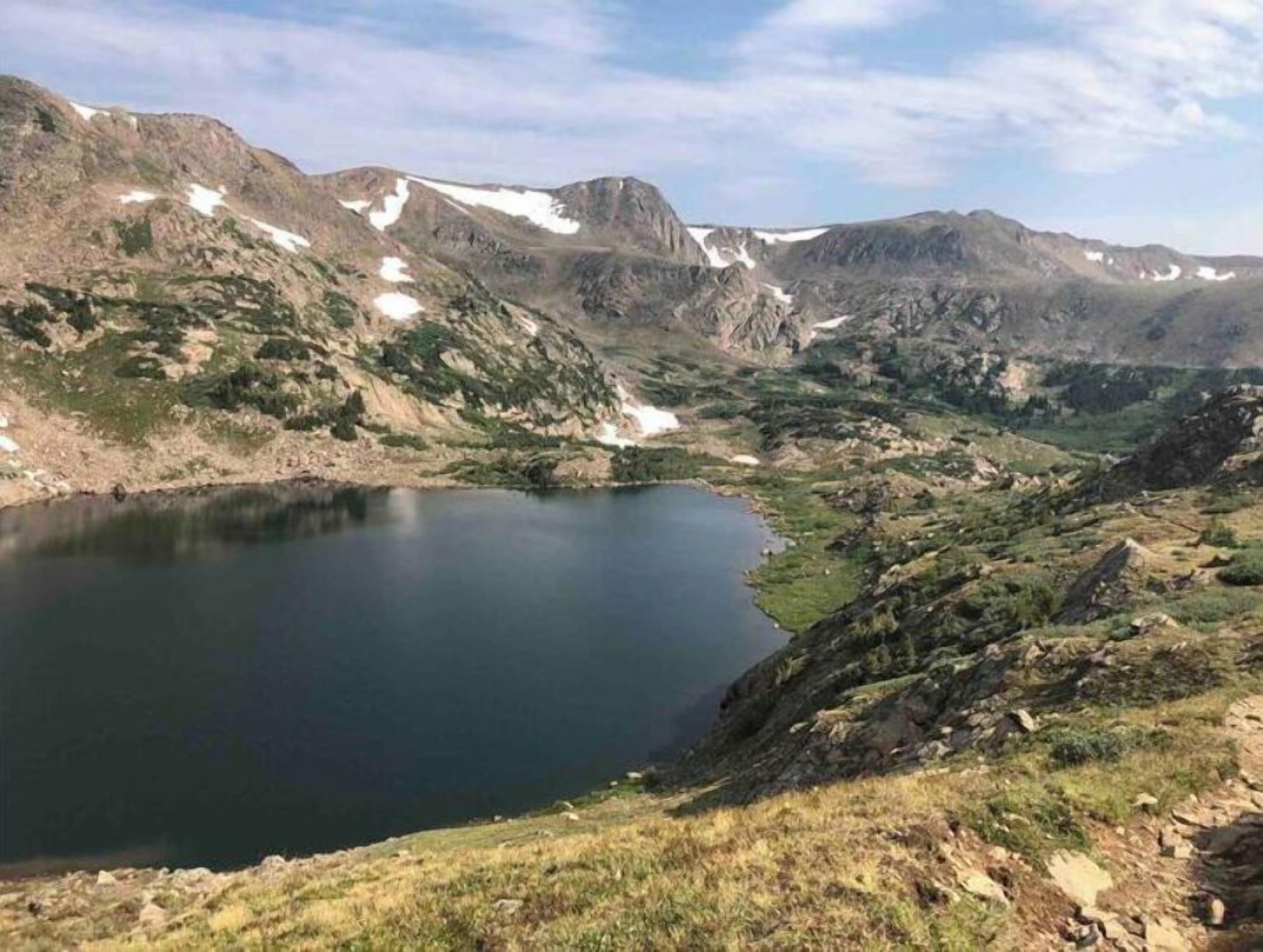 A mountainous landscape with a lake surrounded by rocky terrain and sparse vegetation.