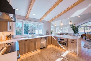 A modern kitchen with wooden cabinets, a large island, and a view of the outdoors. - Wonderland Lake Retreat w/ 5 bedrooms and 3 ensuites. 10min bike to Pearl St. (Boulder)