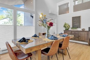 A dining area with a glass-top table, wooden chairs, and a vase with flowers. - Wonderland Lake Retreat w/ 5 bedrooms and 3 ensuites. 10min bike to Pearl St. (Boulder)