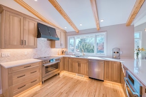 Una cocina moderna con armarios de madera, electrodomésticos de acero inoxidable y un ventanal que proporciona luz natural.