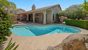 A house with a swimming pool, a patio with outdoor furniture, and a well-maintained garden.