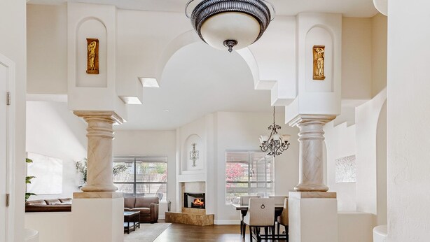A spacious interior with a grand staircase, a chandelier, and a decorative floor pattern.