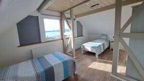 A bedroom with two beds, a window with a view of the sea, and a wooden ceiling. - HM - Holiday home 3 Deluxe Krombachtalsperre Westerwald (Driedorf)