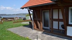 A wooden building with a red-tiled roof, a large window, and a door. - HM - Holiday home 3 Deluxe Krombachtalsperre Westerwald (Driedorf)