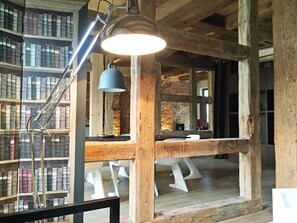 Une bibliothèque rustique avec des étagères en bois, un bureau avec une lampe et un mur en pierre.