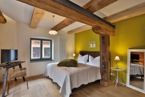 Une chambre à coucher comprenant un lit, une télévision, un fauteuil en osier, une lampe et une fenêtre.